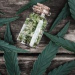 un bocal en verre rempli de feuilles de marijuana sur une table en bois.